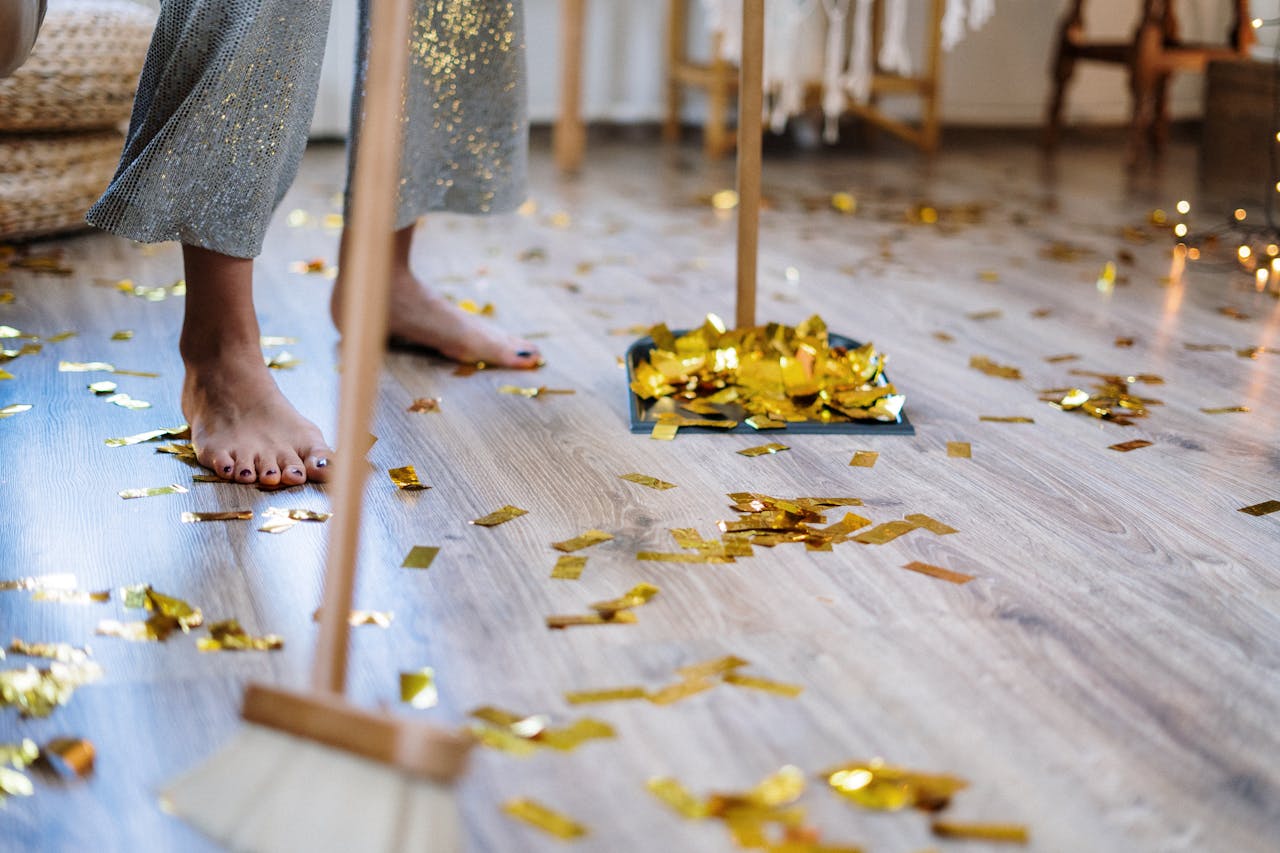 Woman cleaning up confetti after a party at home, symbolizing tidiness and chores.